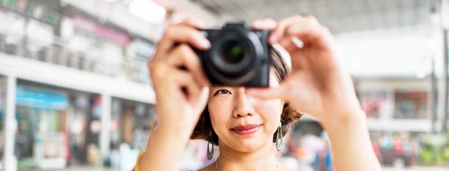 woman taking a photo with a mirrorless camera for photography terms article