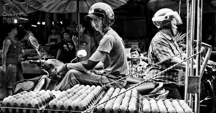 man on a motorcycle with a side car full of trays of eggs