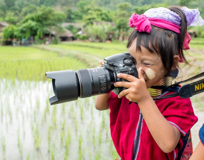 Kayan long neck girl taking photos with a Nikon DLSR camera during a Chiang Mai Photo Workhsop