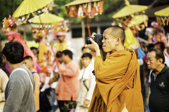 Buddhist monk taking a photo during the Poi Sang Long festival in Mae Hong Son, Thailand.