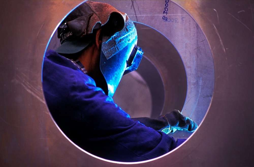 Aluminium welder wearing protective clothing working.