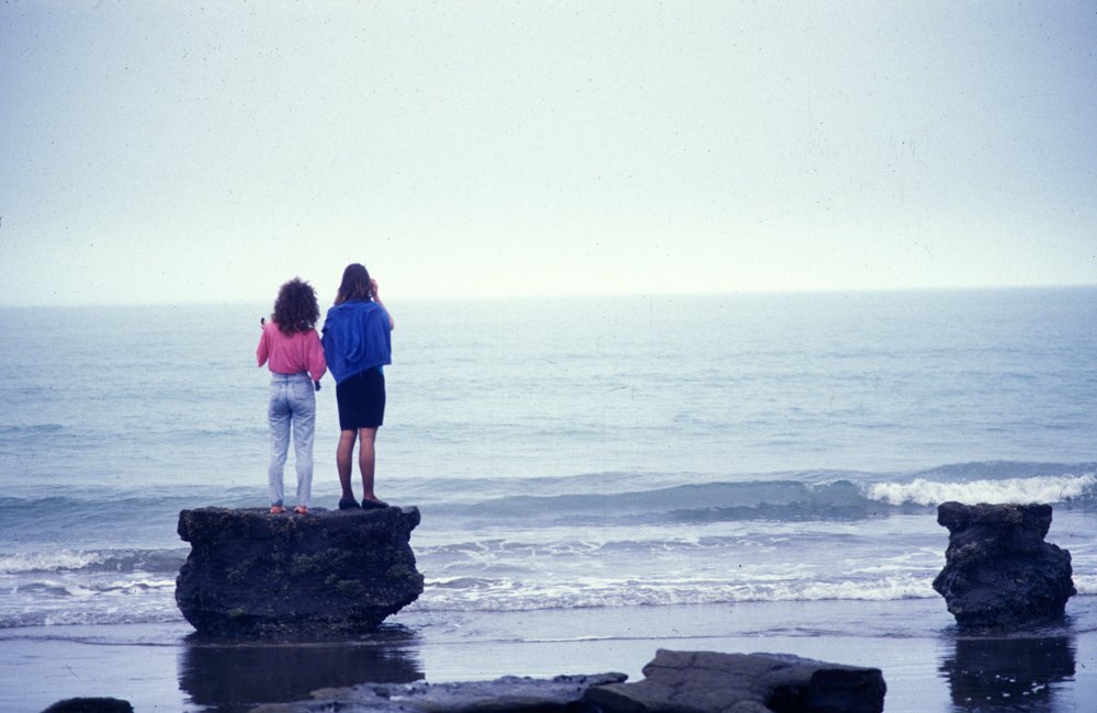 Women standing on a rock at the beach. Learning how to photograph people