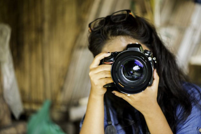 Asian woman using a DSLR camera, lens fungs can be a problem