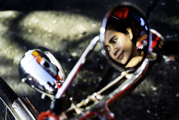 Reflection of a Thai woman in a bike mirror at Muang Mai Market in Chiang Mai. how to tell stories with photos